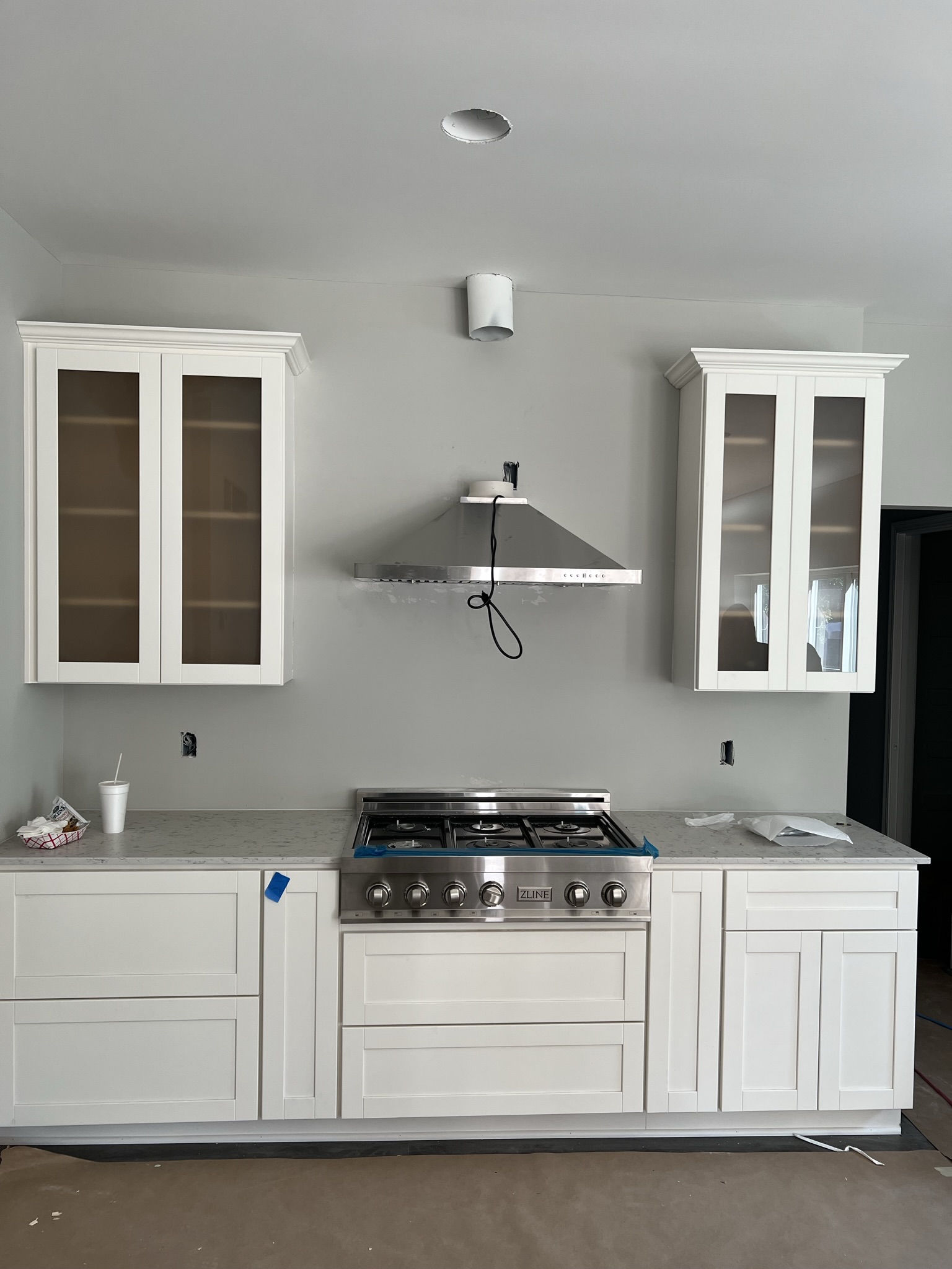 Custom white kitchen with pro-grade ZLINE range and glass upper cabinets during install