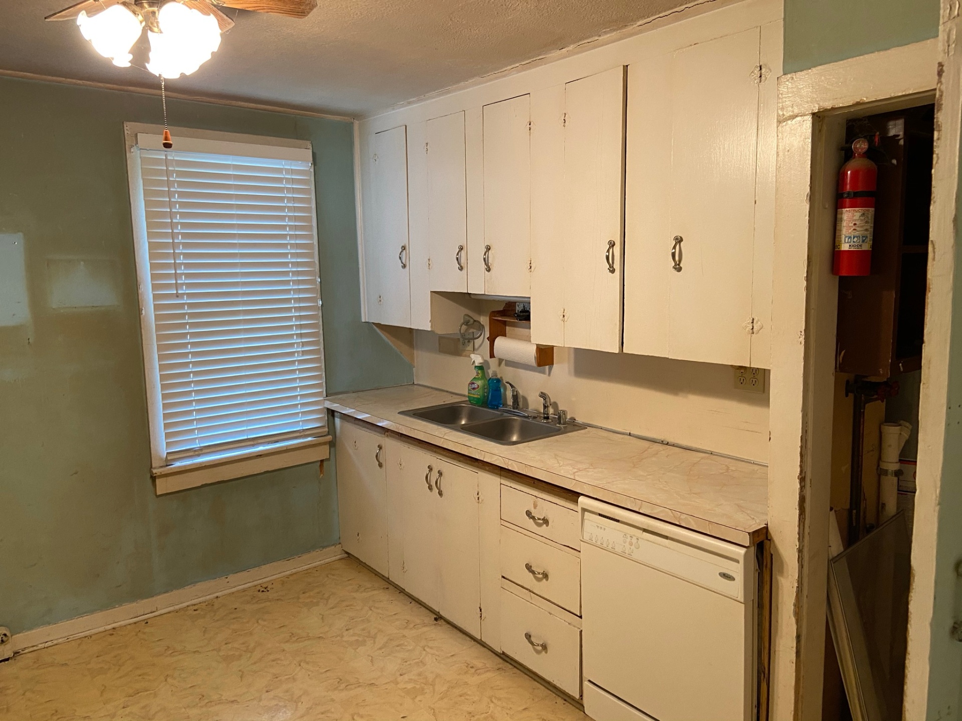 Original kitchen before remodel — worn white cabinets, laminate counter, aqua walls and vinyl floor
